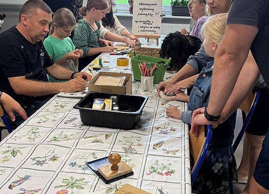 Dzieci siedzące przy stole wykonują zadania plastyczne.