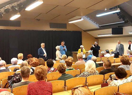 Na pierwszym planie, tyłem,  słuchacze, którzy patrzą w stronę składających podziękowania.